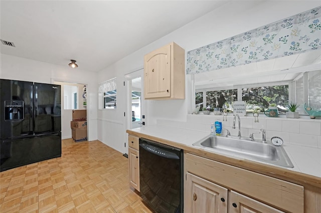 kitchen with a healthy amount of sunlight, light brown cabinetry, black appliances, a sink, and visible vents