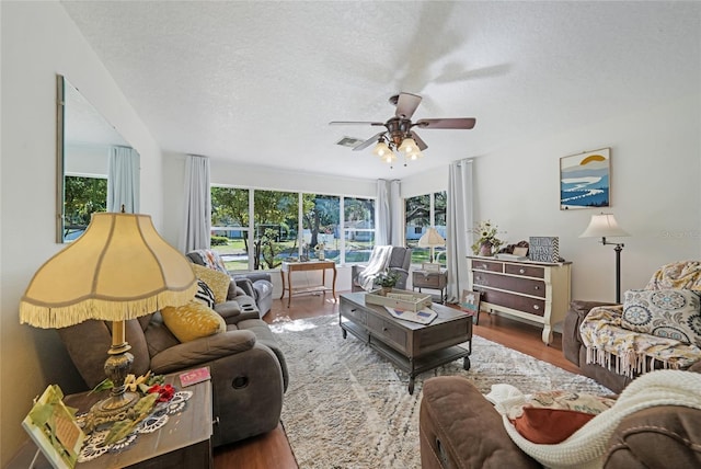 living room featuring wood finished floors, a ceiling fan, a textured ceiling, and plenty of natural light