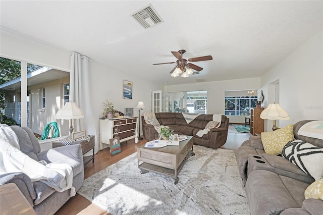 living area with a ceiling fan, visible vents, and wood finished floors
