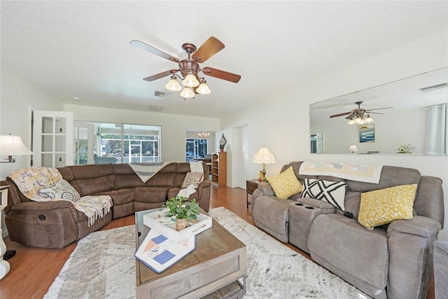 living area featuring a ceiling fan, visible vents, and wood finished floors