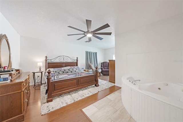 bedroom featuring a ceiling fan, light wood-style flooring, and a textured ceiling
