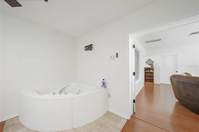 bathroom with baseboards, visible vents, a tub with jets, and wood finished floors