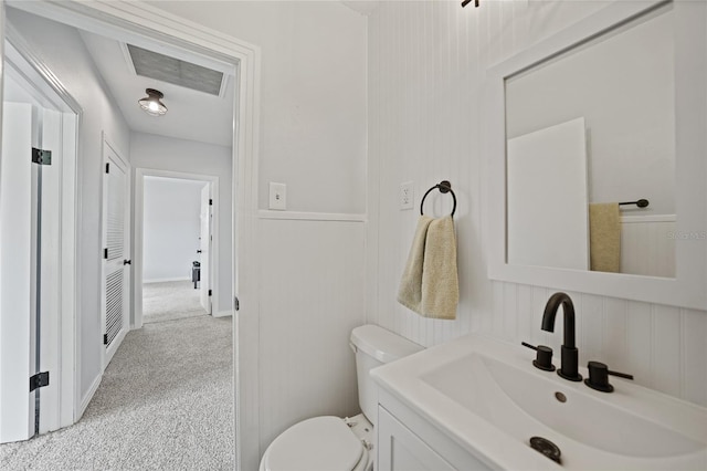 half bathroom with toilet, a wainscoted wall, visible vents, and vanity