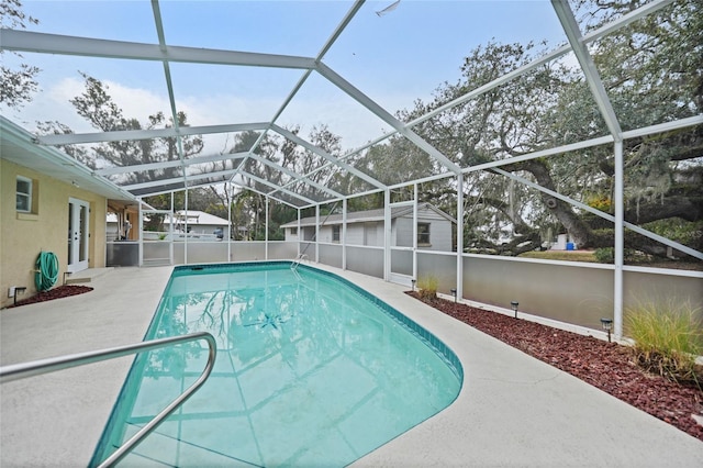 view of pool with a patio area, an outdoor structure, a fenced in pool, a lanai, and a storage unit