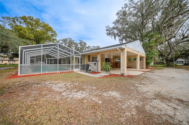 rear view of property with cooling unit, a patio area, and glass enclosure