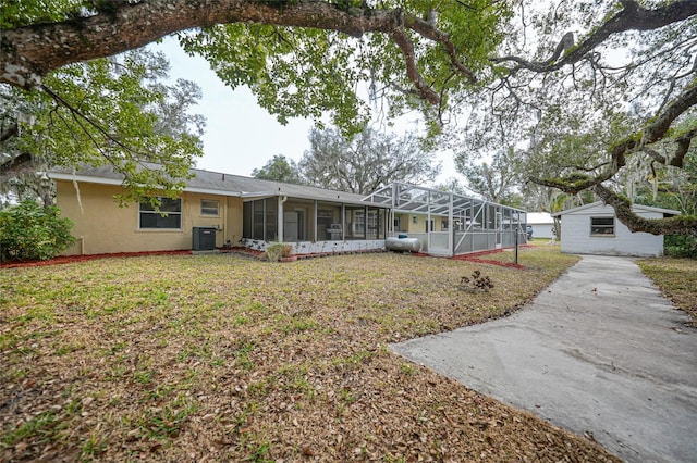 view of front of home featuring a front yard, a sunroom, central AC, a lanai, and stucco siding