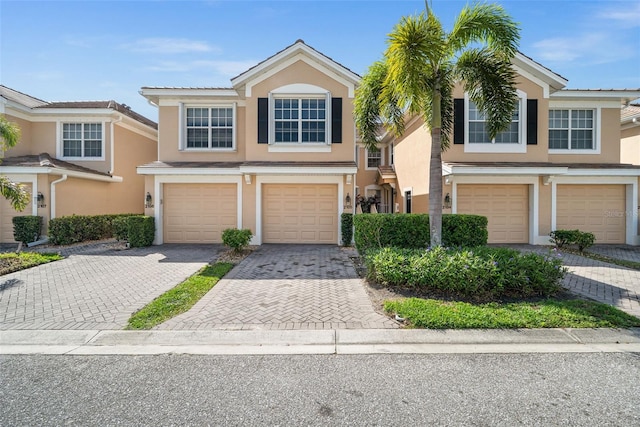 townhome / multi-family property featuring stucco siding, driveway, and an attached garage