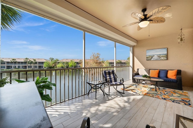 sunroom featuring a ceiling fan and a water view