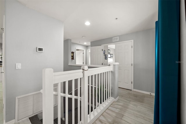 hallway featuring an upstairs landing, visible vents, light wood-style floors, baseboards, and recessed lighting