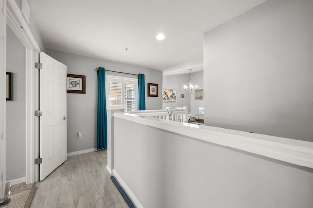 hallway featuring recessed lighting, an upstairs landing, baseboards, light wood-type flooring, and a notable chandelier
