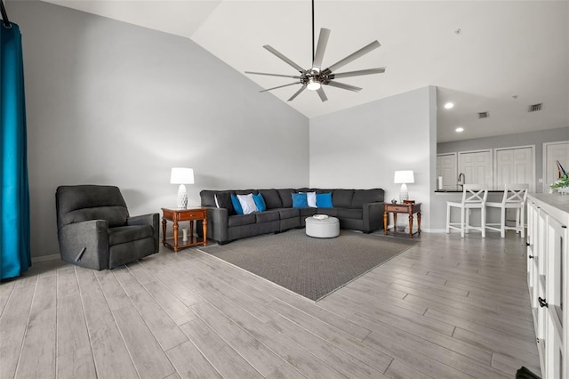 living room with ceiling fan, vaulted ceiling, wood finished floors, and visible vents
