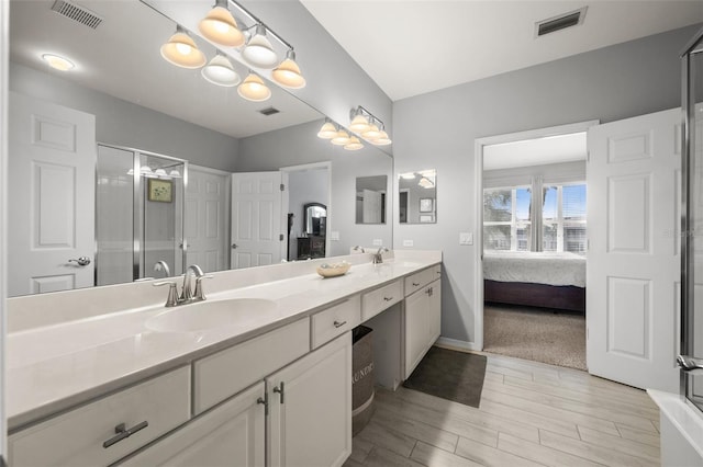 full bathroom with double vanity, wood finished floors, visible vents, and a sink