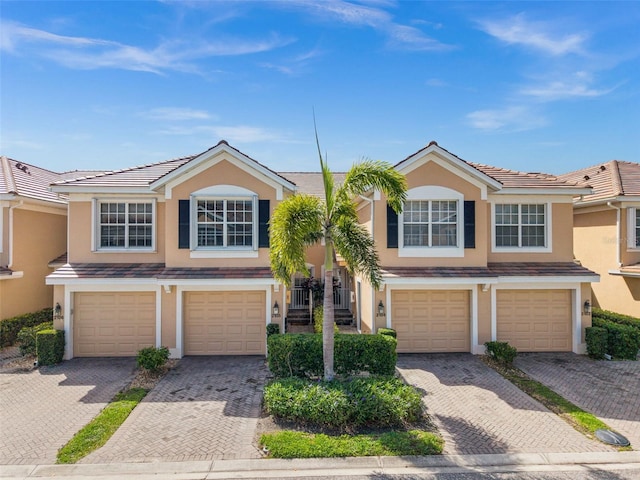 multi unit property featuring stucco siding, a tiled roof, and driveway