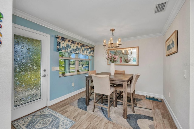 dining space with visible vents, wood finished floors, a notable chandelier, and crown molding