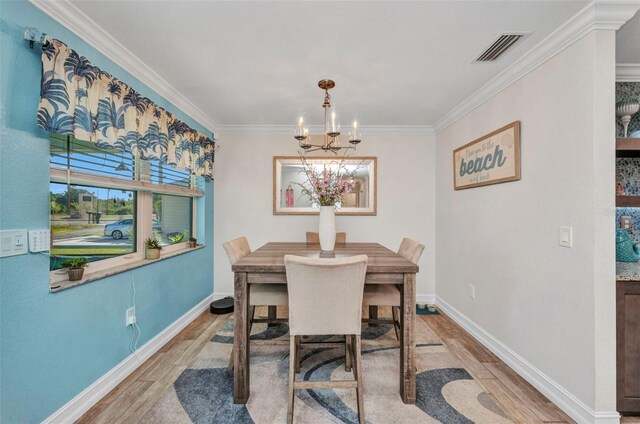dining space with visible vents, baseboards, ornamental molding, wood finished floors, and a notable chandelier