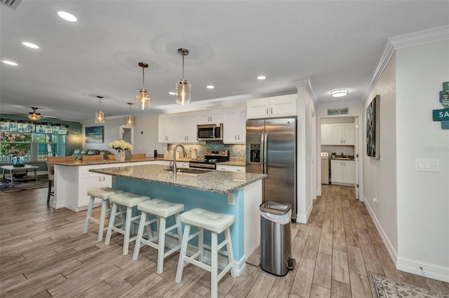 kitchen with light wood-type flooring, stainless steel appliances, crown molding, and a sink