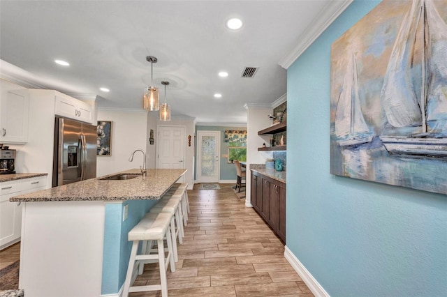 kitchen featuring recessed lighting, stainless steel fridge, ornamental molding, a sink, and visible vents