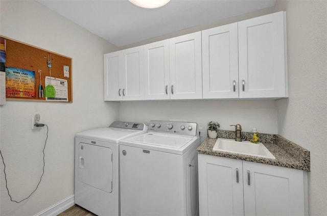 clothes washing area featuring a sink, washing machine and clothes dryer, cabinet space, and baseboards