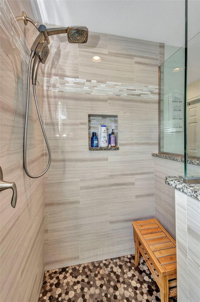 bathroom with tiled shower and tile patterned flooring