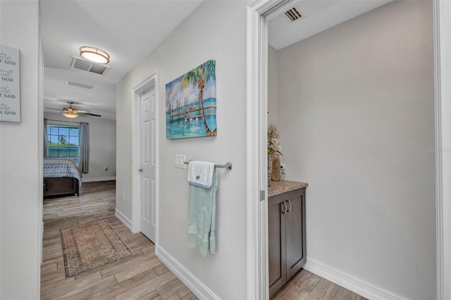 hallway with visible vents, light wood-type flooring, and baseboards