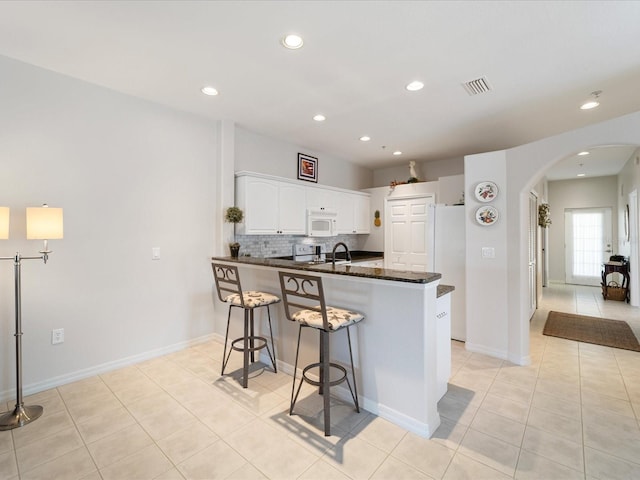 kitchen with light tile patterned floors, visible vents, white appliances, and arched walkways