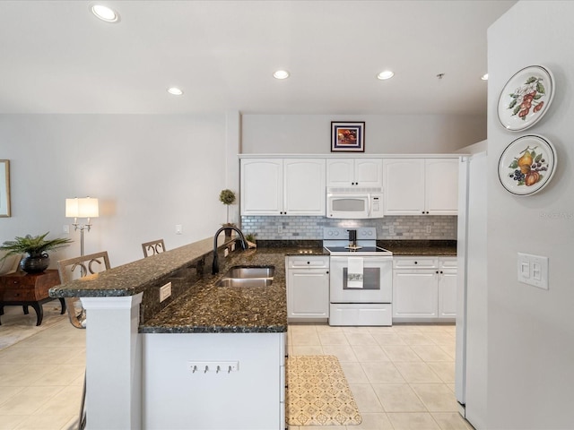 kitchen featuring white cabinets, a sink, light tile patterned flooring, white appliances, and a peninsula