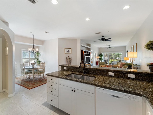 kitchen with dark stone counters, white cabinets, a sink, white dishwasher, and arched walkways