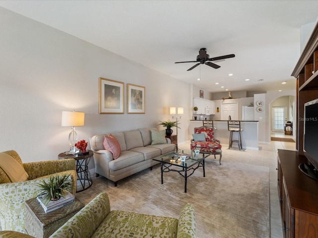 living area featuring light tile patterned floors, arched walkways, a ceiling fan, and recessed lighting