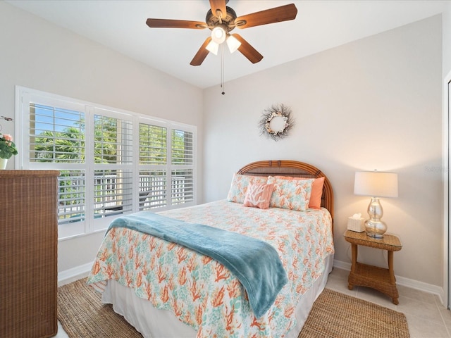 bedroom featuring baseboards, tile patterned flooring, a ceiling fan, and multiple windows