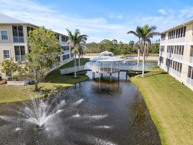 dock area with a gazebo, a water view, and a lawn