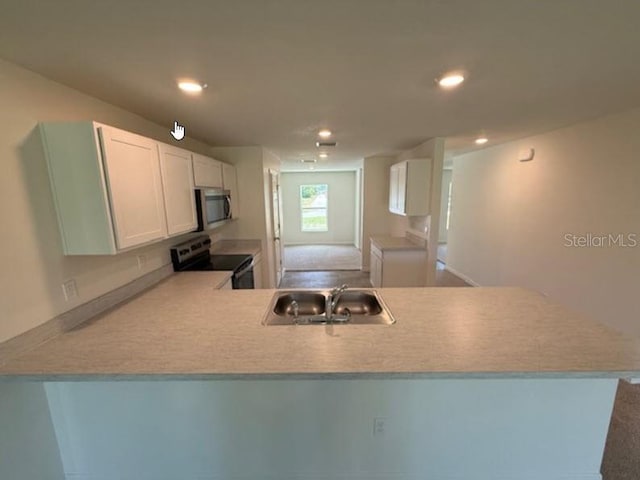 kitchen featuring washer / dryer, a peninsula, white cabinets, a sink, and appliances with stainless steel finishes