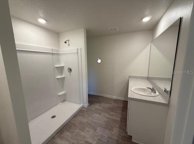 bathroom featuring baseboards, walk in shower, visible vents, and vanity