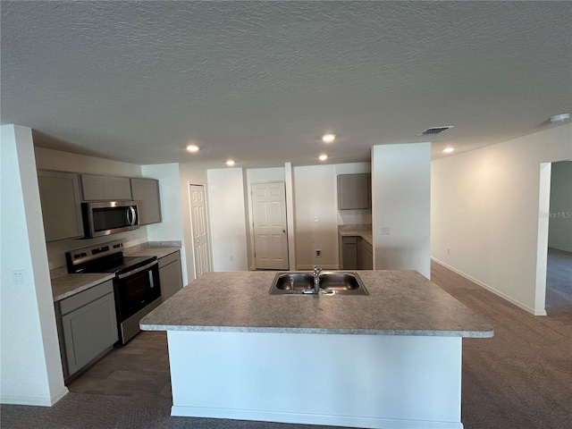 11 Zorro Ct, Palm Coast, FL 32164 - kitchen with carpet floors, a kitchen island with sink, a sink, appliances with stainless steel finishes, and gray cabinetry