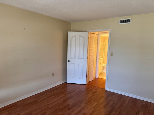 unfurnished bedroom with baseboards, wood finished floors, and visible vents