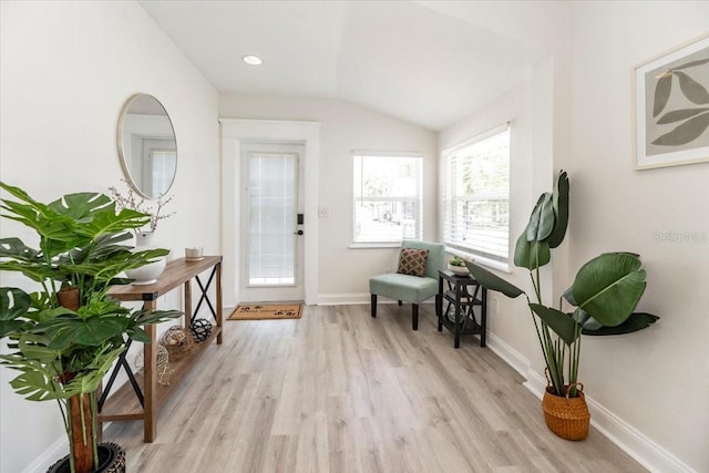 foyer entrance with baseboards, lofted ceiling, and light wood-type flooring