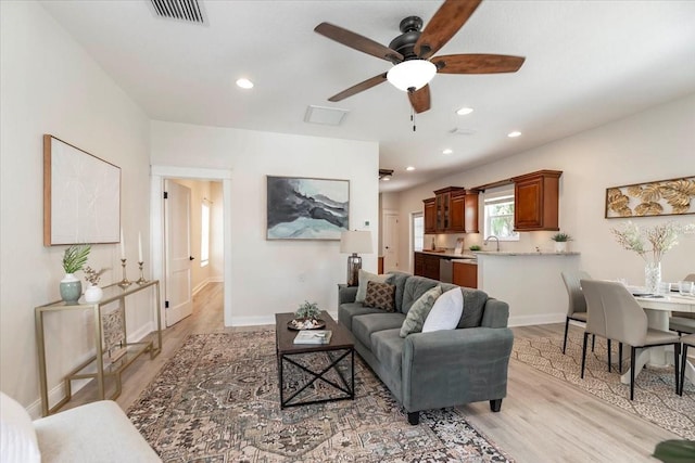 living area featuring visible vents, light wood-type flooring, a ceiling fan, and recessed lighting