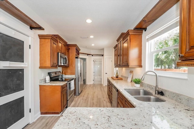 kitchen featuring brown cabinets, a sink, appliances with stainless steel finishes, and light wood-type flooring