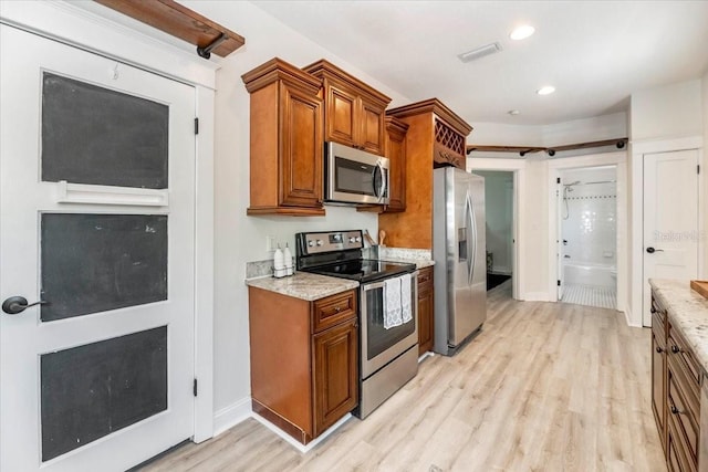 kitchen with brown cabinets, stainless steel appliances, light wood-type flooring, and visible vents