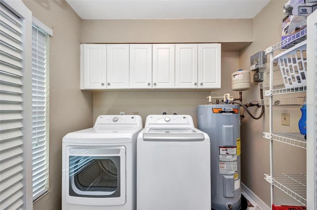 washroom with cabinet space, a healthy amount of sunlight, washer and clothes dryer, and water heater