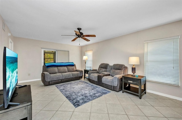 living area featuring a ceiling fan, baseboards, and light tile patterned floors