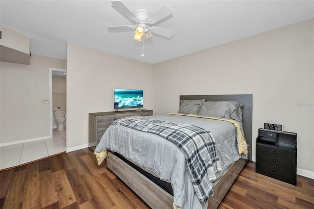 bedroom featuring baseboards, ensuite bath, ceiling fan, and wood finished floors