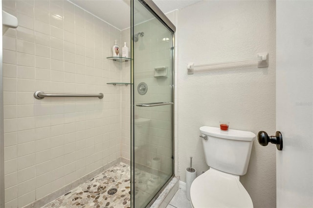 bathroom featuring tile patterned floors, a shower stall, and toilet