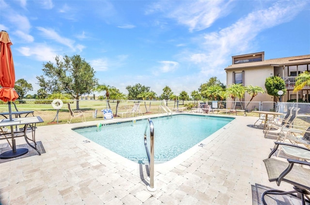 community pool with a patio and fence