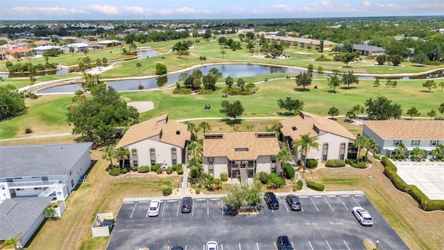drone / aerial view featuring a water view, view of golf course, and a residential view