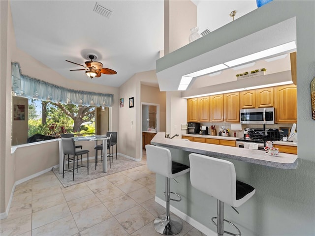 2288 Prague Ln, Punta Gorda, FL 33983 - kitchen with visible vents, baseboards, a kitchen bar, electric range oven, and stainless steel microwave