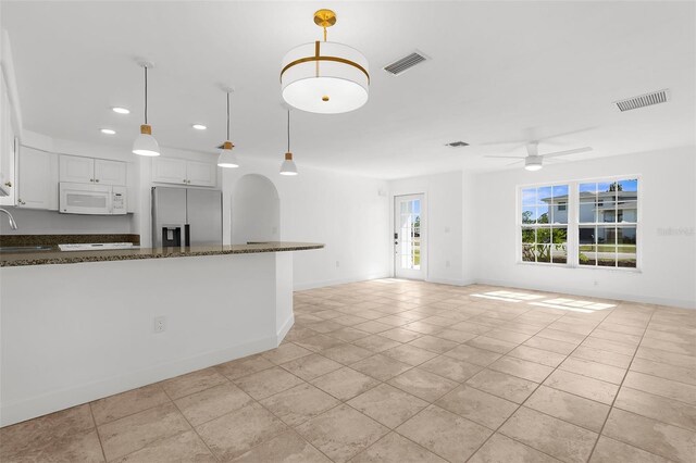 124 Rotonda Cir, Rotonda West, FL 33947 - kitchen featuring white microwave, stainless steel fridge with ice dispenser, a sink, white cabinetry, and visible vents