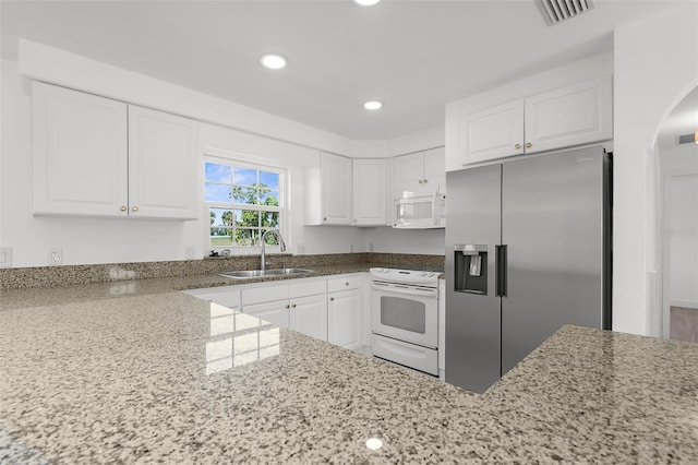 124 Rotonda Cir, Rotonda West, FL 33947 - kitchen with light stone counters, visible vents, white appliances, and a sink