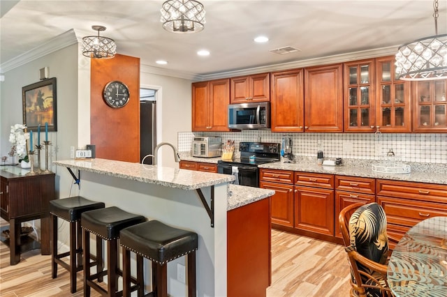 kitchen with appliances with stainless steel finishes, a breakfast bar, light wood-style flooring, and visible vents
