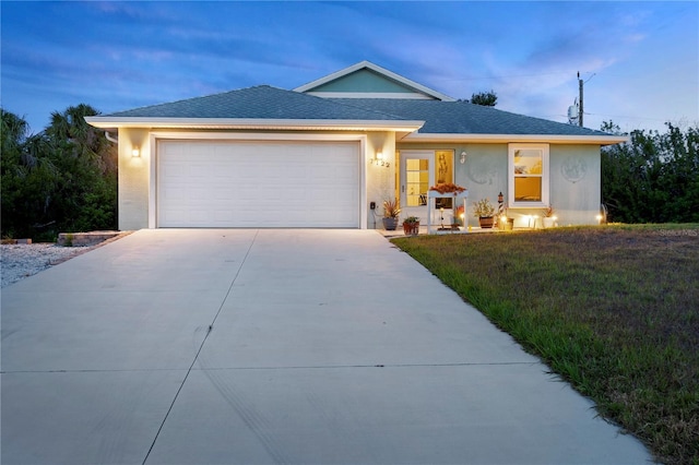 single story home with an attached garage, a shingled roof, stucco siding, and driveway