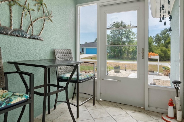 doorway to outside with a textured wall, light tile patterned flooring, and a wealth of natural light